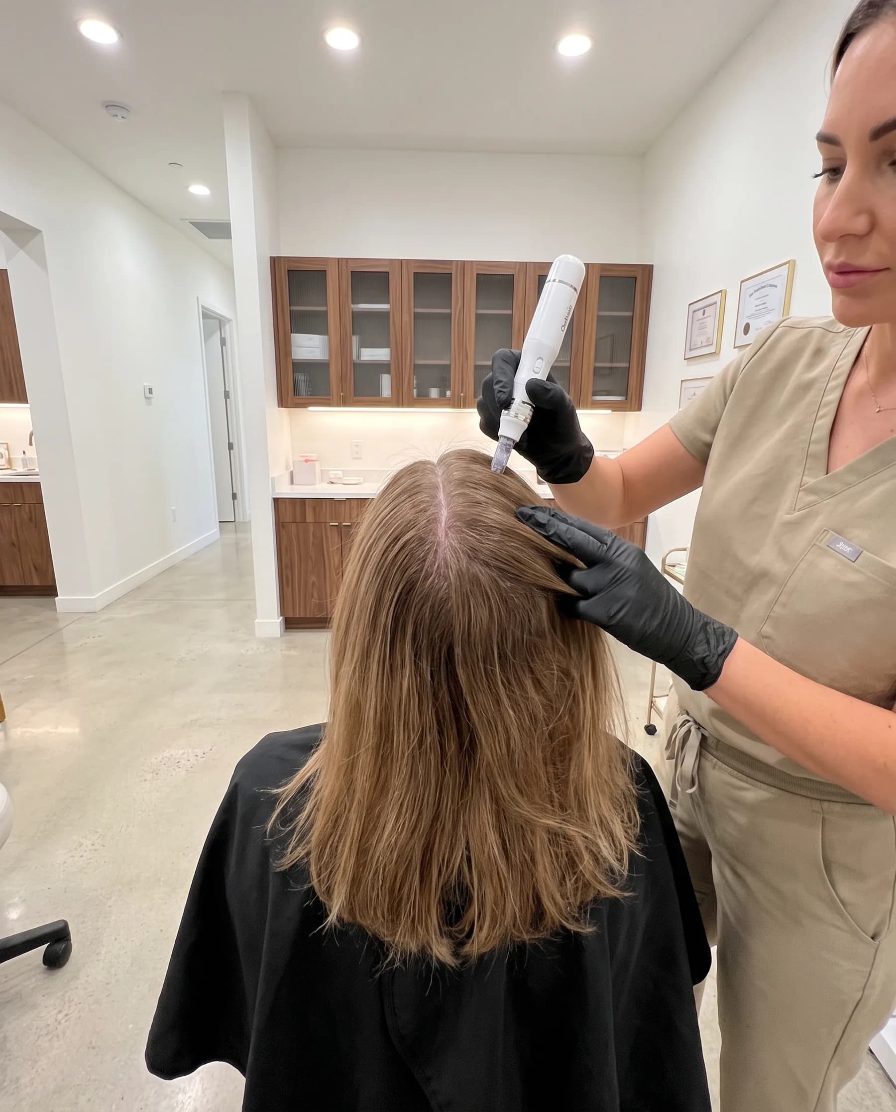 Stylo à micro-aiguilles posé sur une raie du cuir chevelu, cheveux tenus par une main gantée