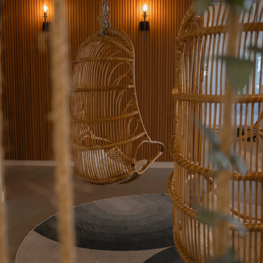 The institute's rest corner: two hanging rattan chairs in front of a pale wood wall