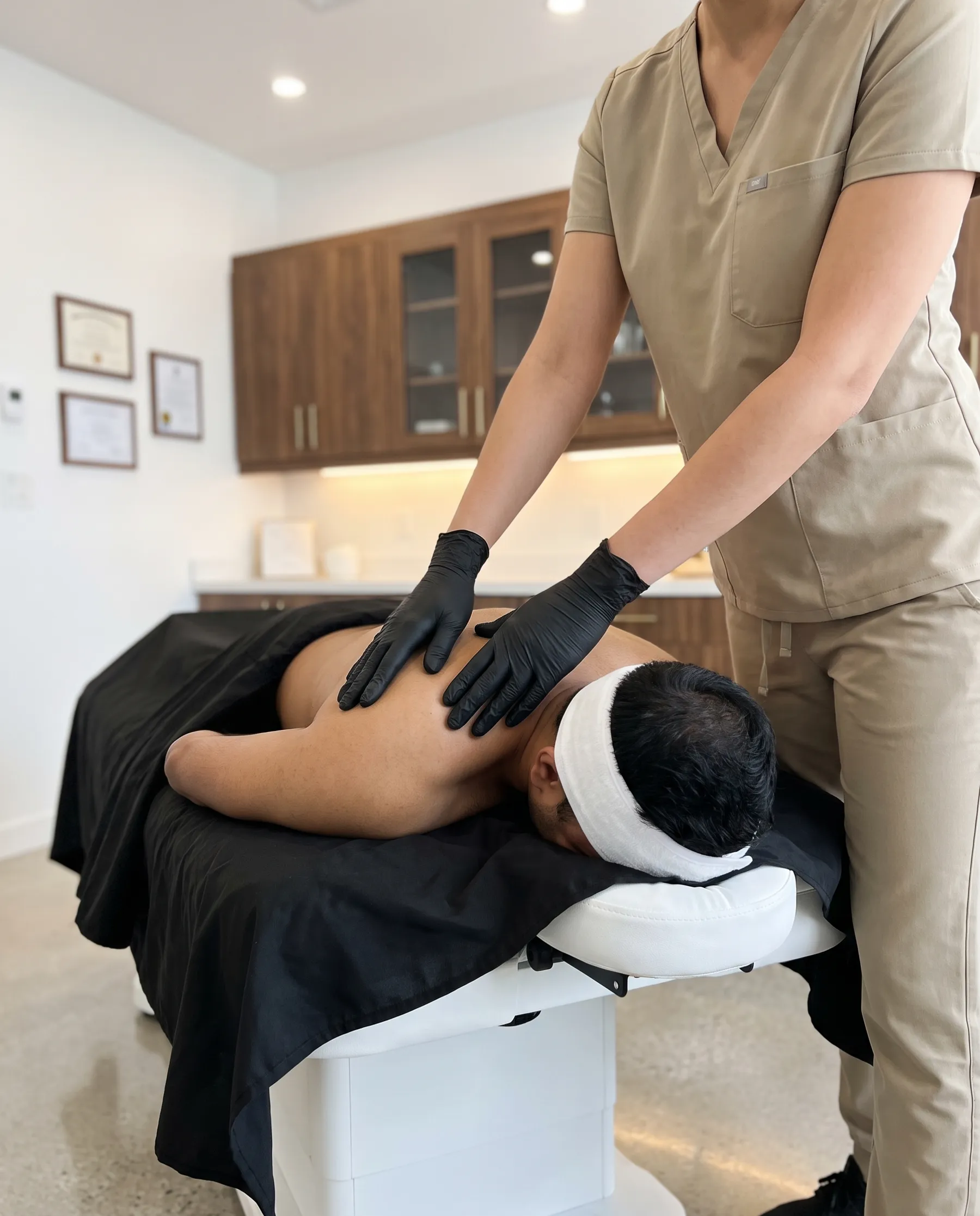 The therapist's hands resting still on a man's shoulder blades