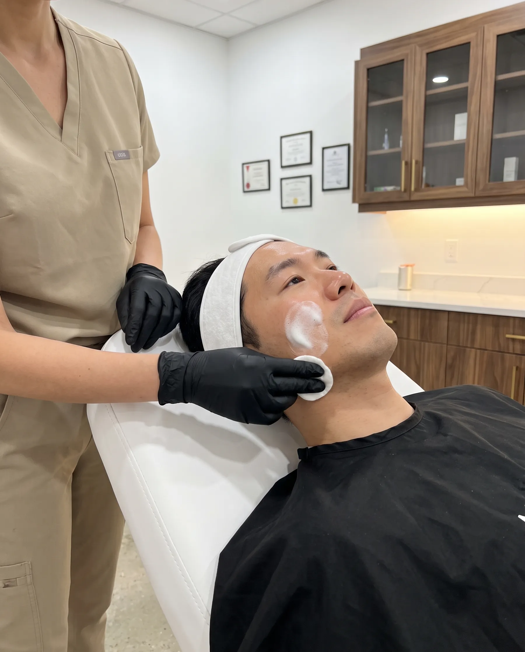A man's face being cleansed with a cotton pad along the jaw