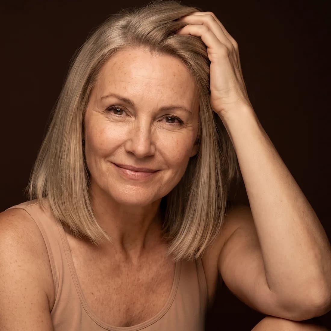 Femme aux cheveux blonds fins, les doigts passés dans ses cheveux sur le dessus de la tête, sourire soulagé