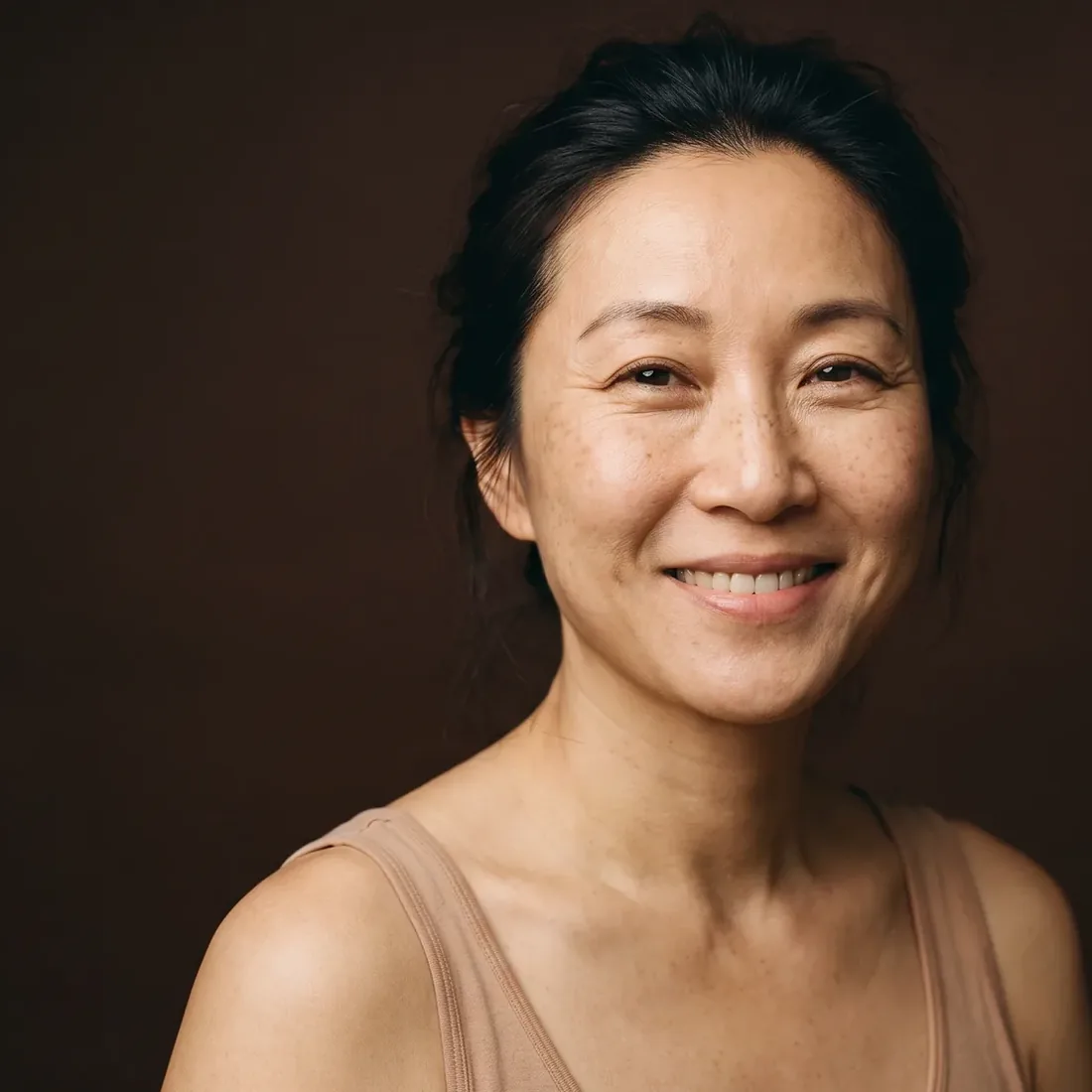Woman with a relaxed smile, forehead smooth and fine lines left visible