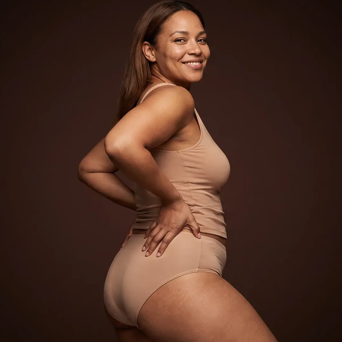 Femme debout de trois quarts, regard par-dessus l'épaule, sourire