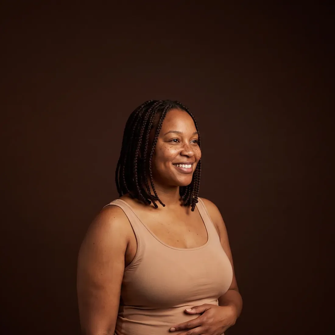 A woman standing in three-quarter view, a hand at her waist, relaxed and smiling