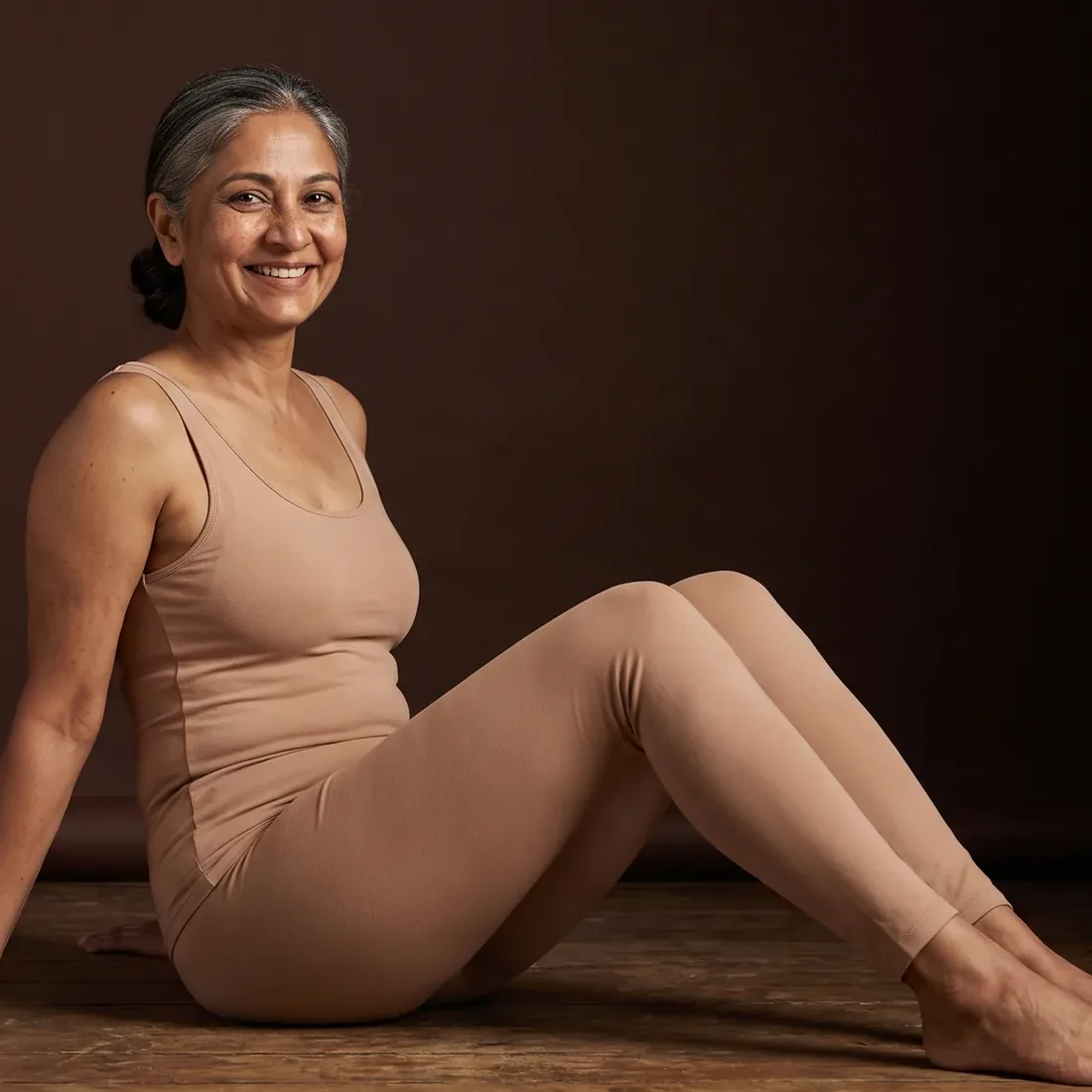Woman sitting on the floor, legs stretched out, relieved smile