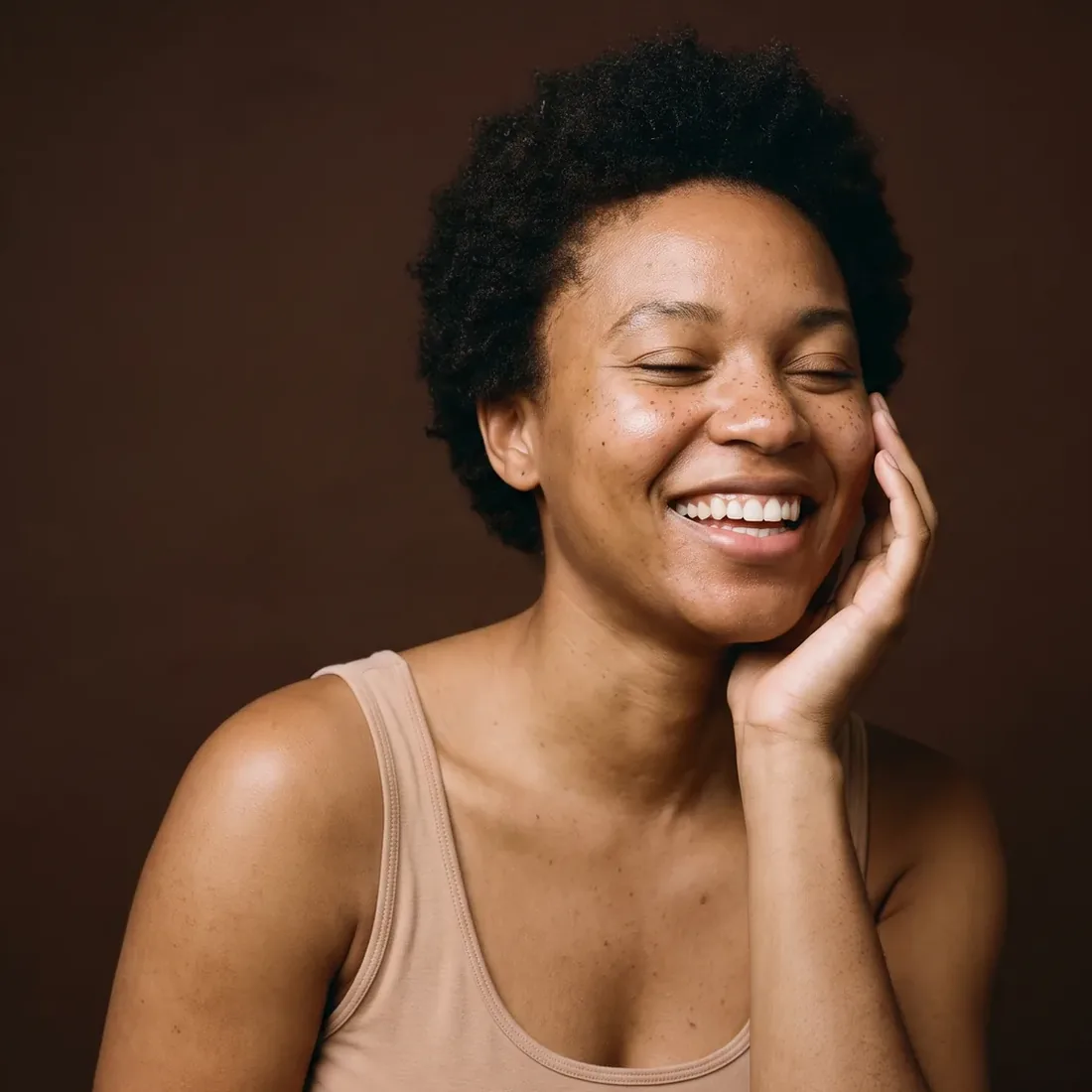 Young woman laughing, eyes closed for a moment, hand on her cheek