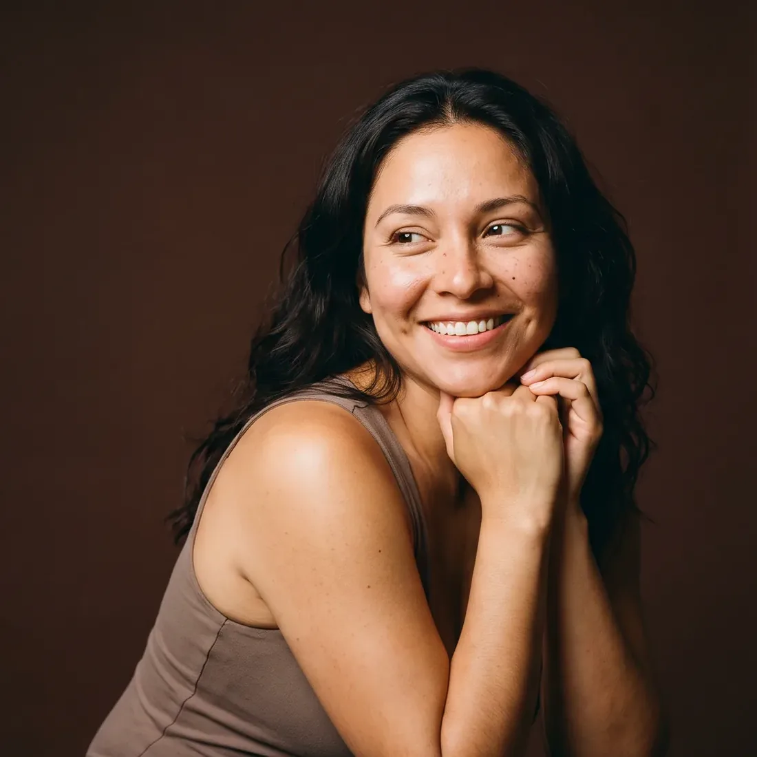 Smiling woman, hands joined under her chin, clear skin