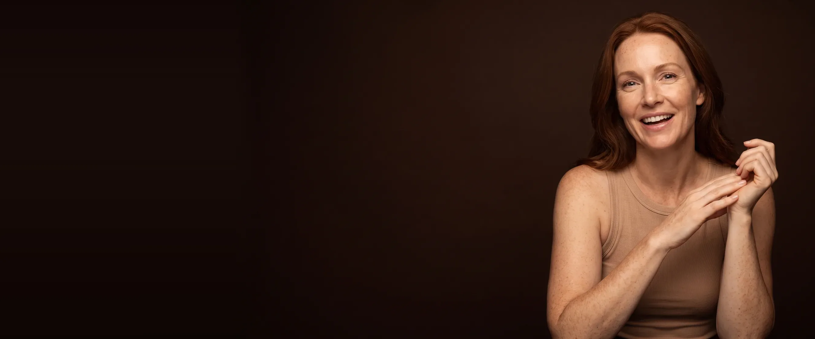 A woman sitting upright, smiling mid-conversation