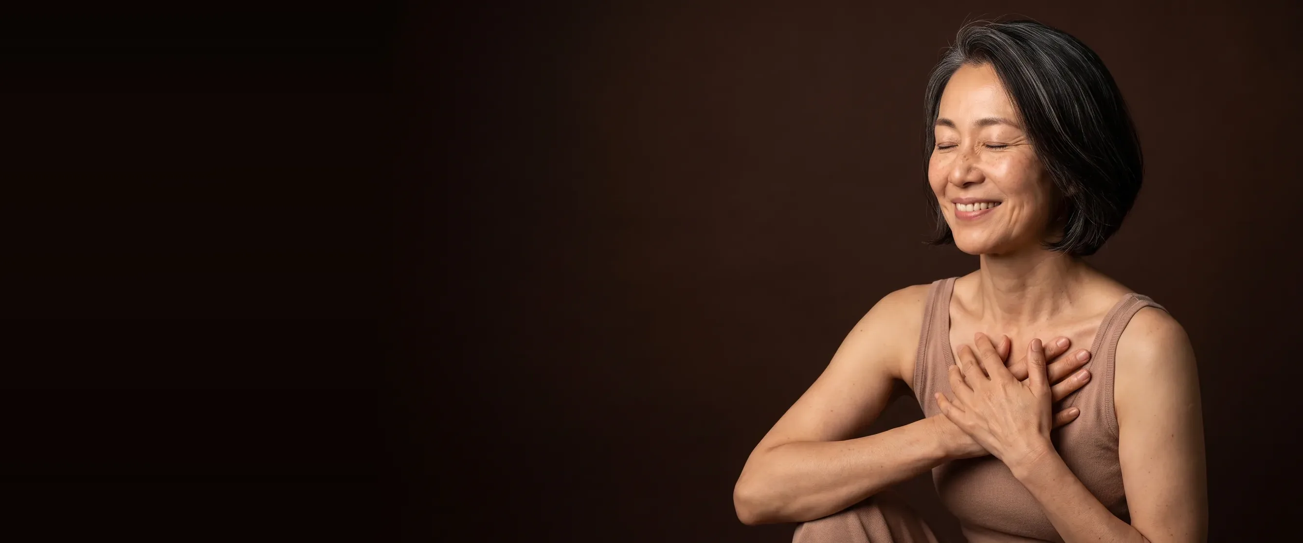 A woman with her eyes closed and her hands over her heart, smiling