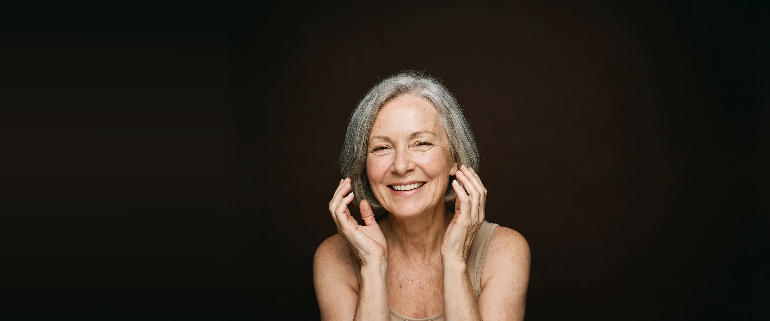 A woman in her sixties, smiling, hands open beside her face