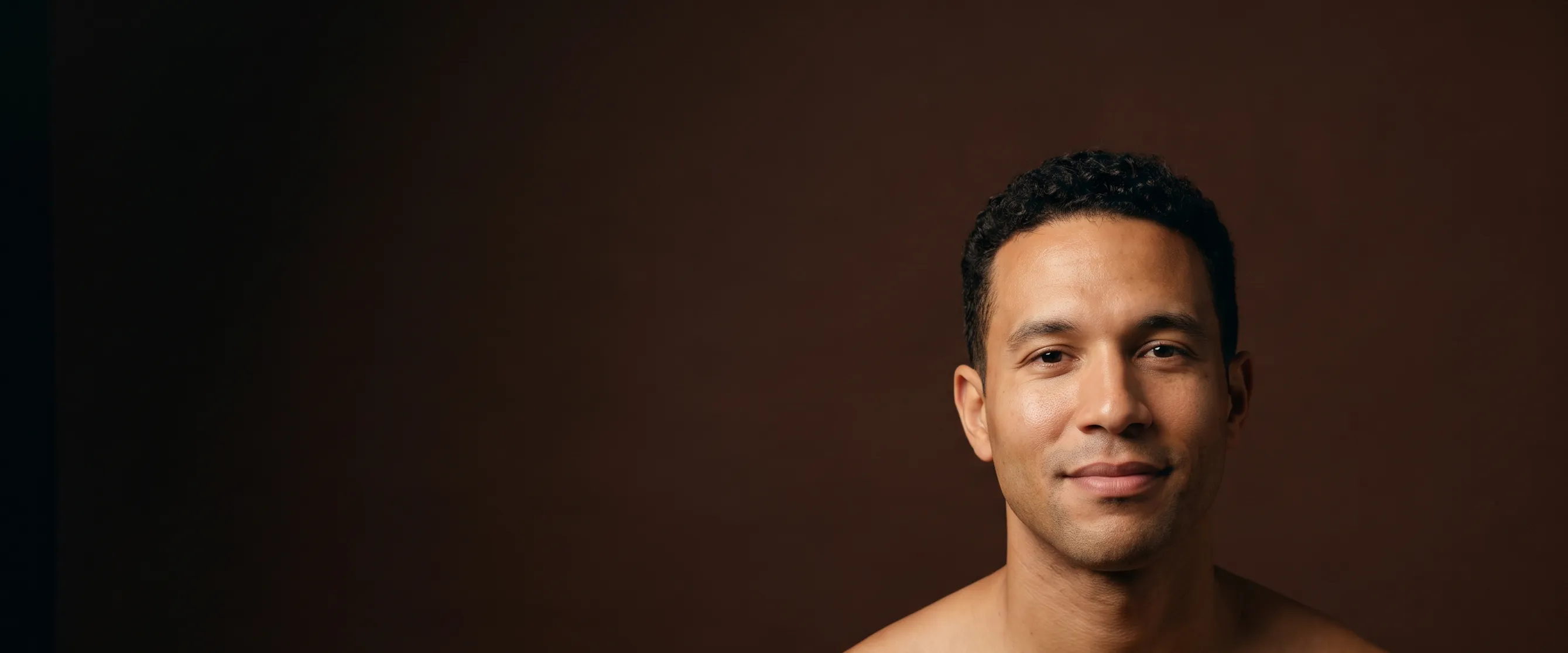 A man of about thirty-six with curly hair, bare shoulders
