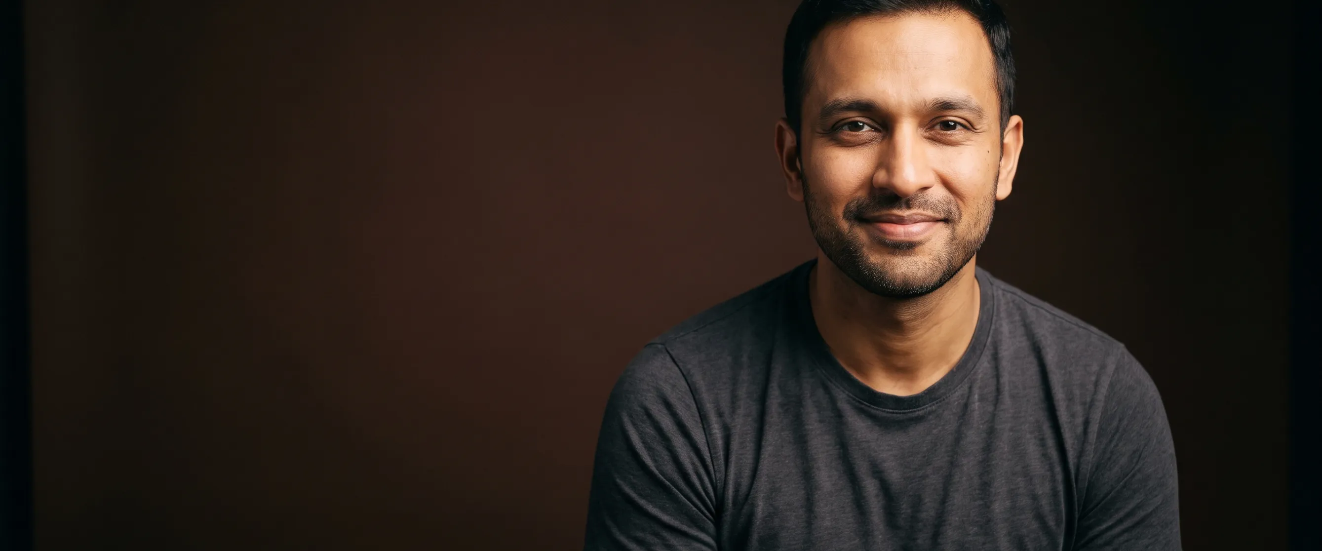 A man of about thirty-six with black hair and neat stubble