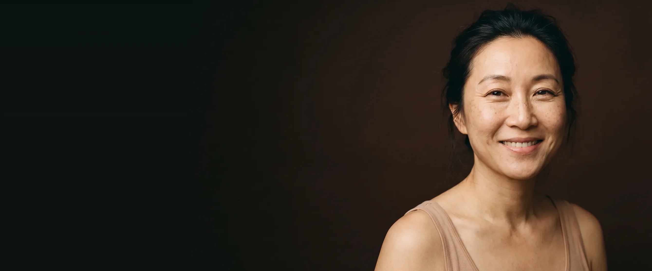 A woman with a relaxed smile, a smooth forehead and her fine lines left visible