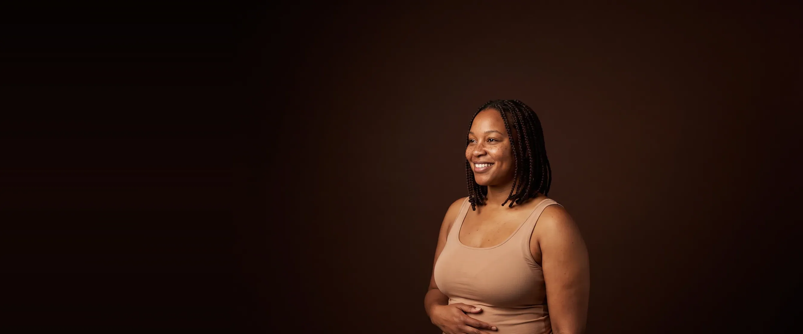 A woman standing in three-quarter view, a hand at her waist, relaxed and smiling