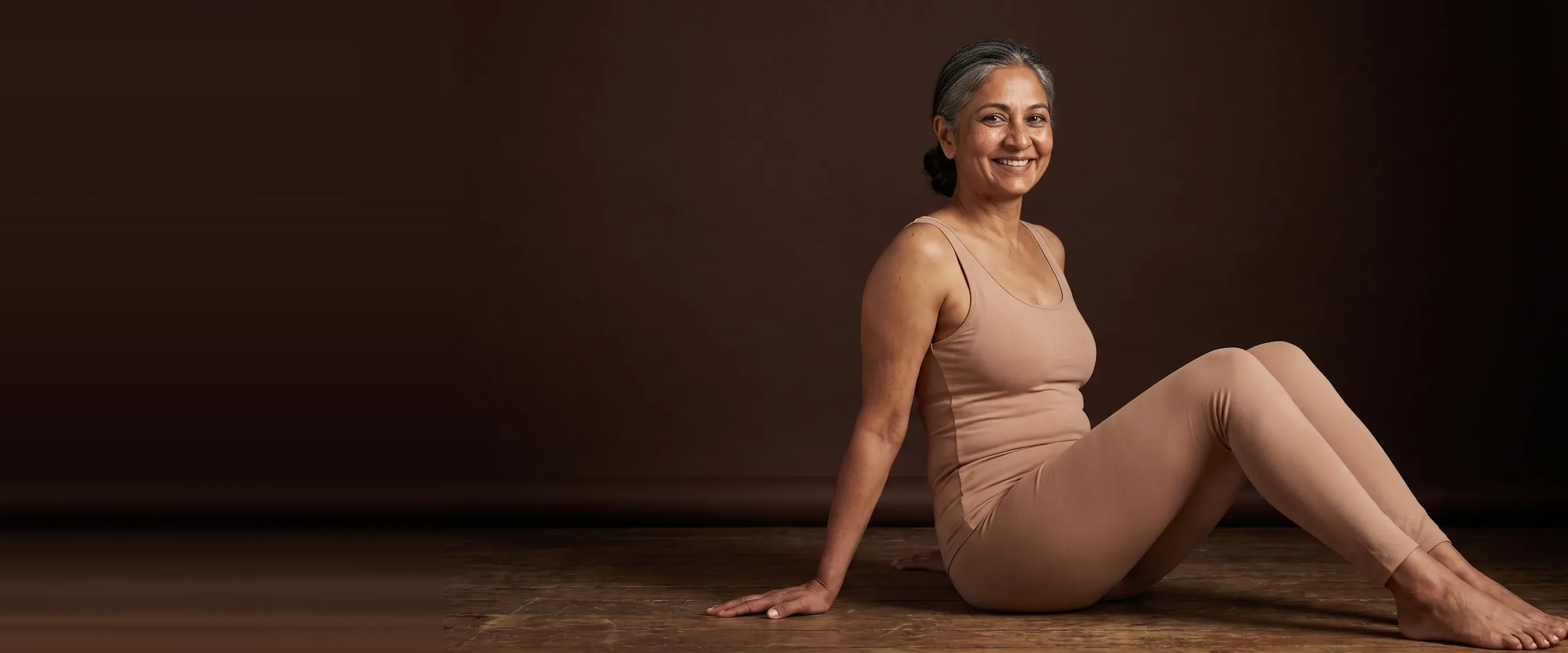 Femme assise au sol, jambes tendues, sourire soulagé