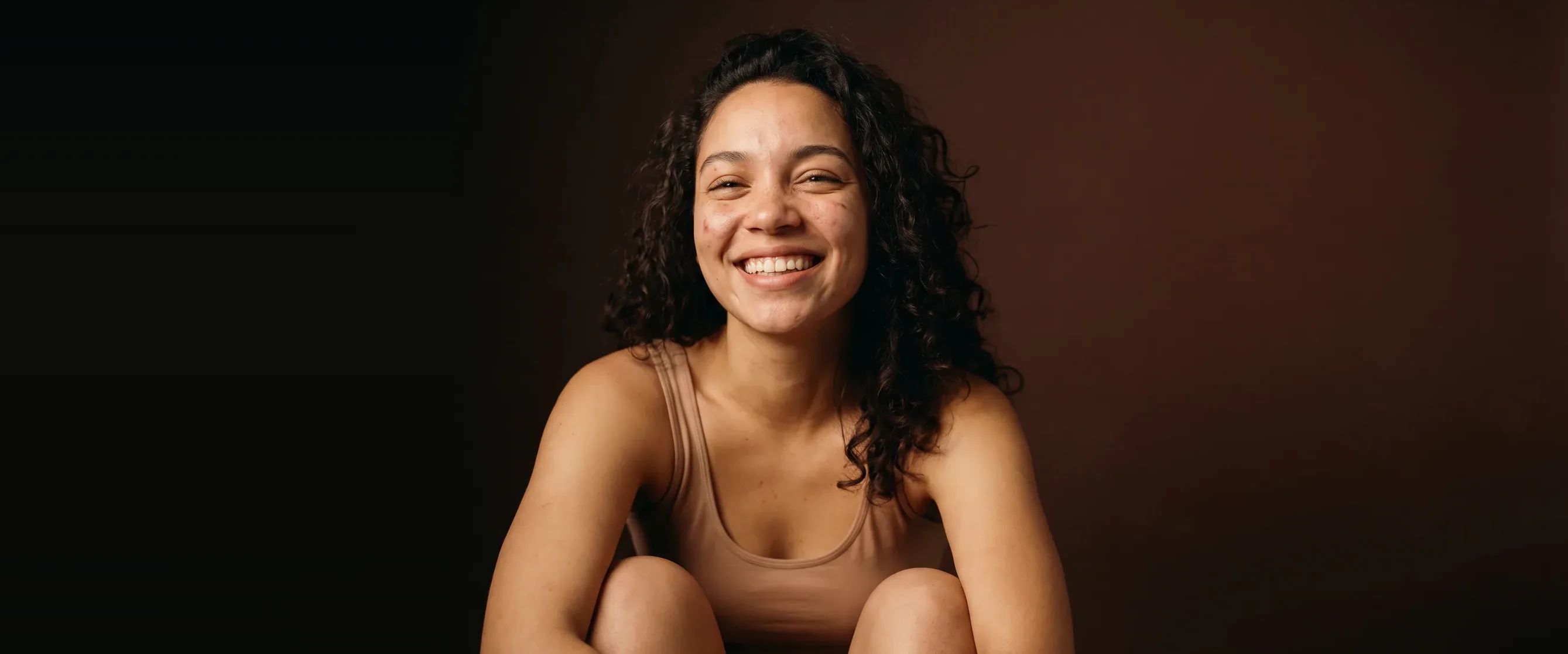 A young woman laughing, head tipped back a little, skin clear and healthy