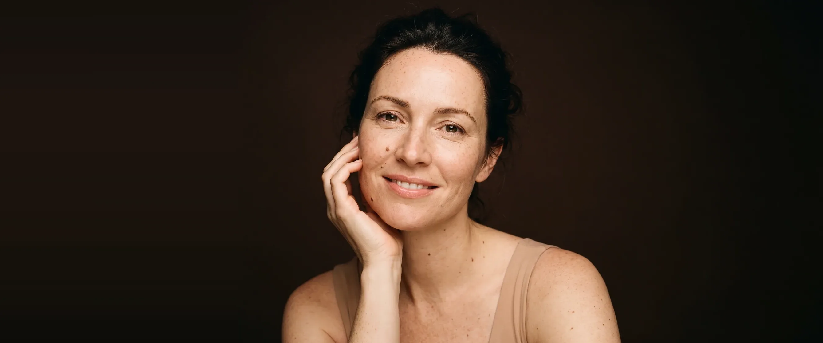 A smiling woman, luminous skin, her fine lines left visible