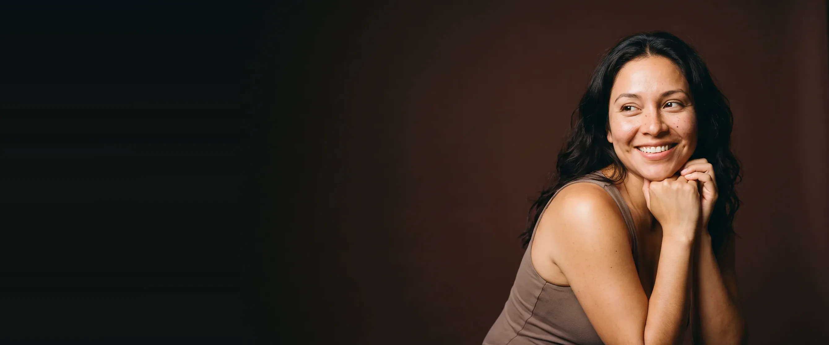 A smiling woman, hands clasped under her chin, skin clear